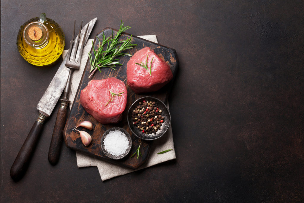 Raw fillet steak cooking on stone table. Top view with space for your text